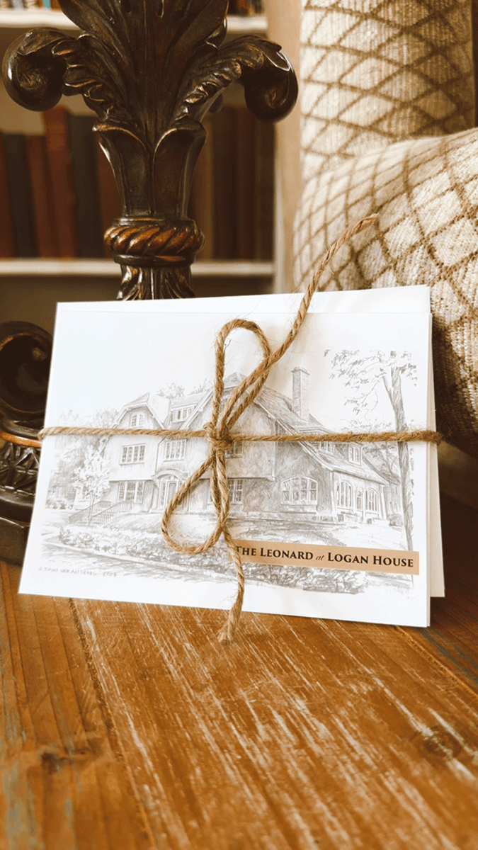A wrapped illustration of the Leonard at Logan House resting on a wooden table.