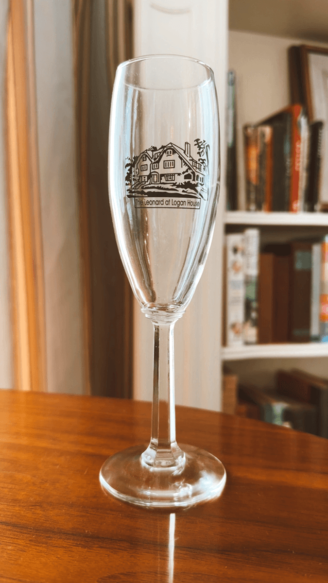 A clear champagne flute featuring a graphic of the Leonard at Logan House.