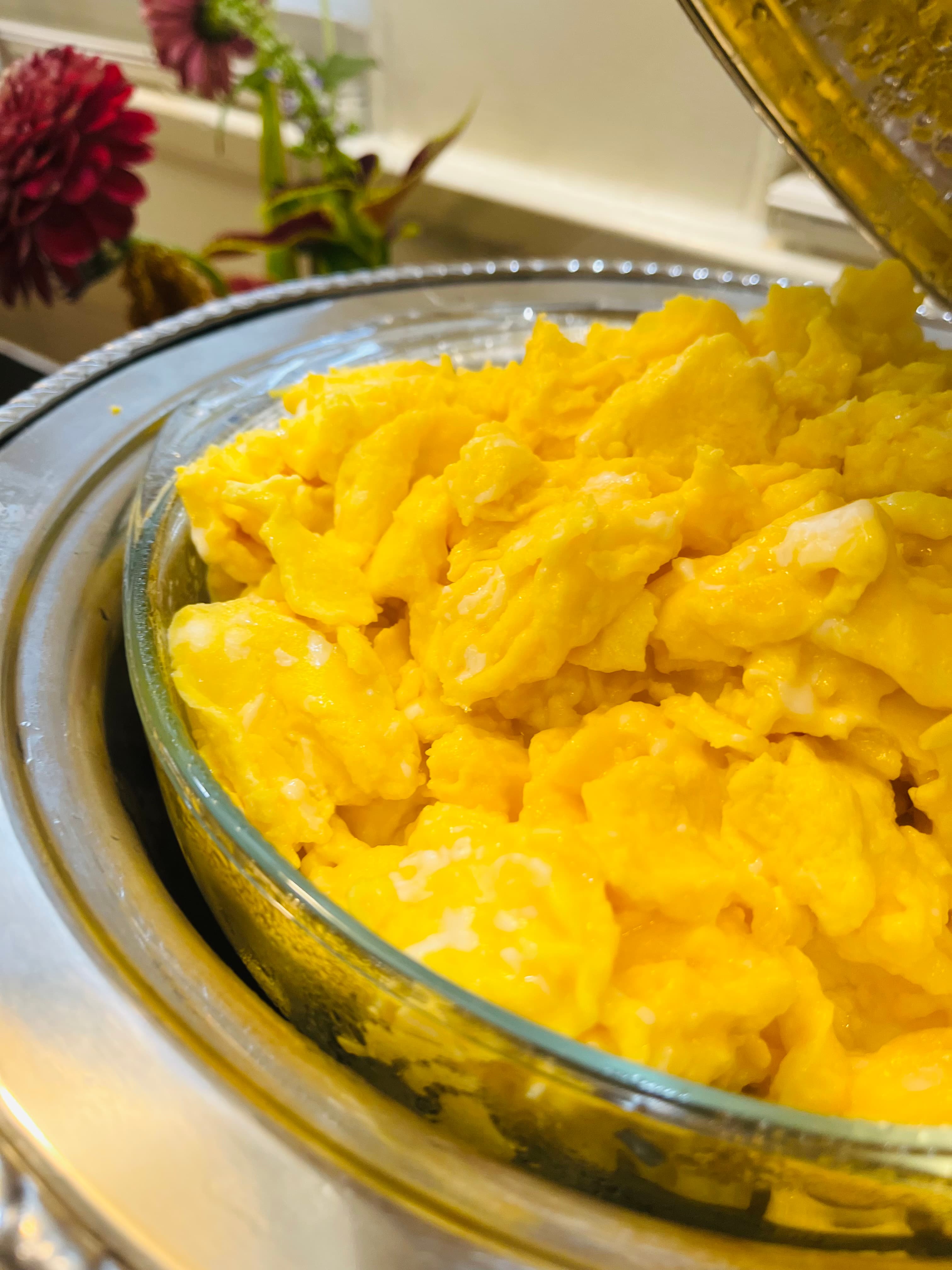 A glass dish filled with fluffy, yellow scrambled eggs.