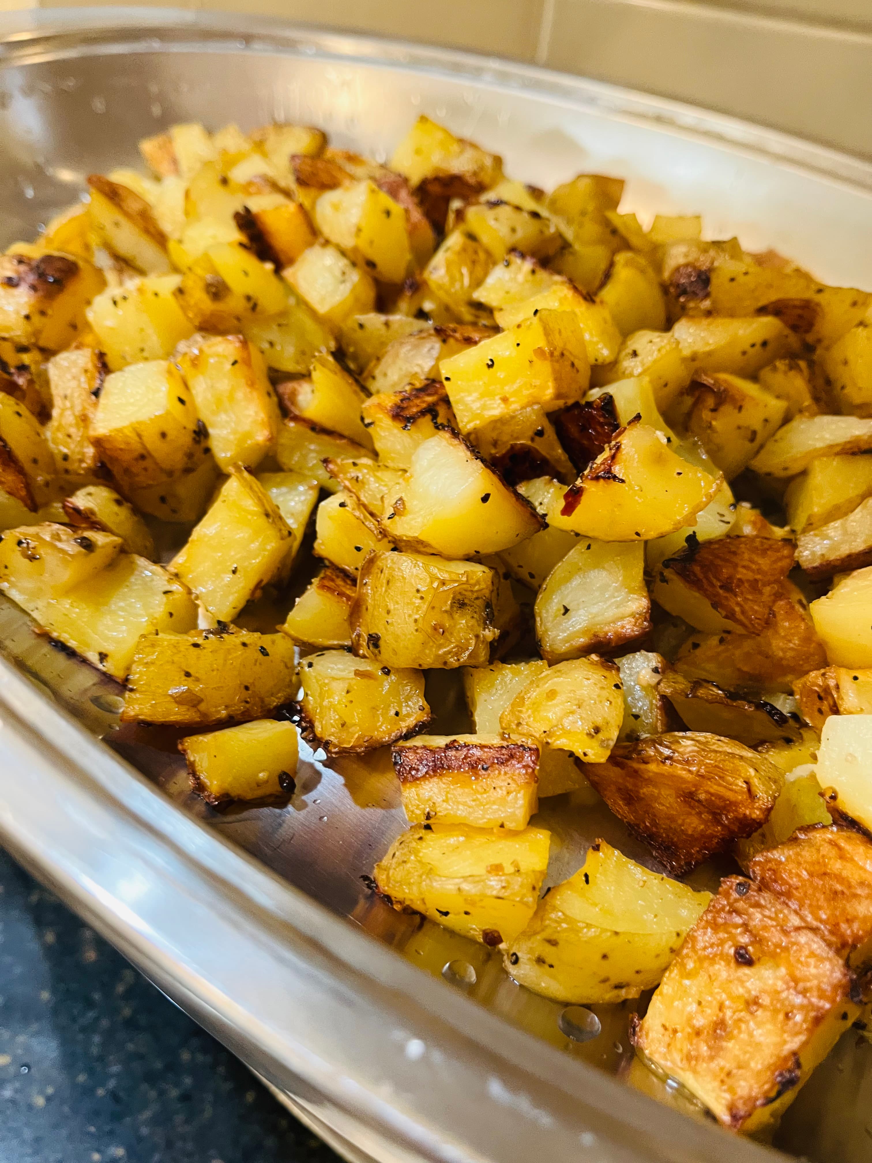A close-up of crispy, golden-brown roasted potatoes seasoned with herbs.