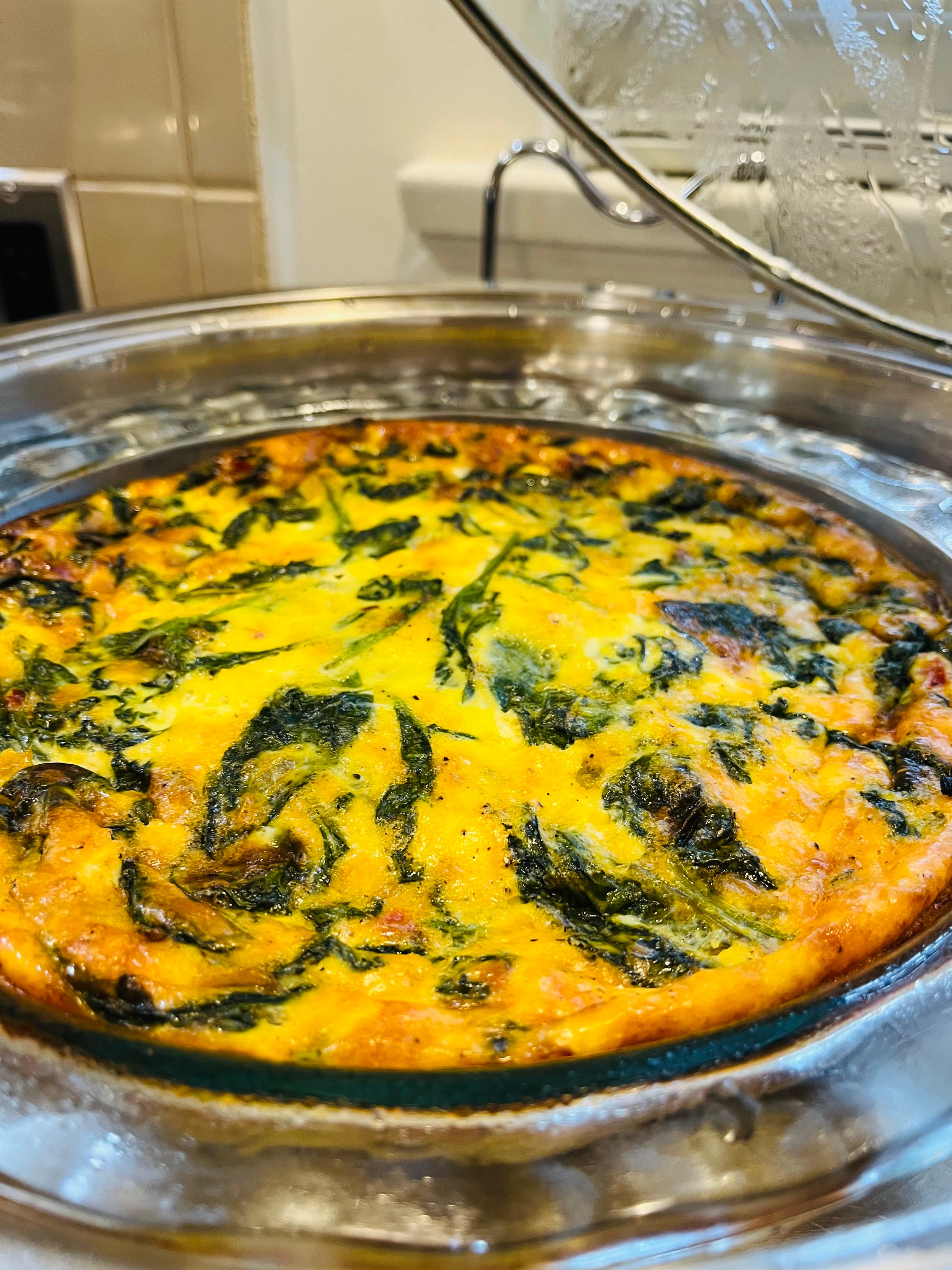 A baked dish with a golden yellow crust and dark green leafy vegetables.