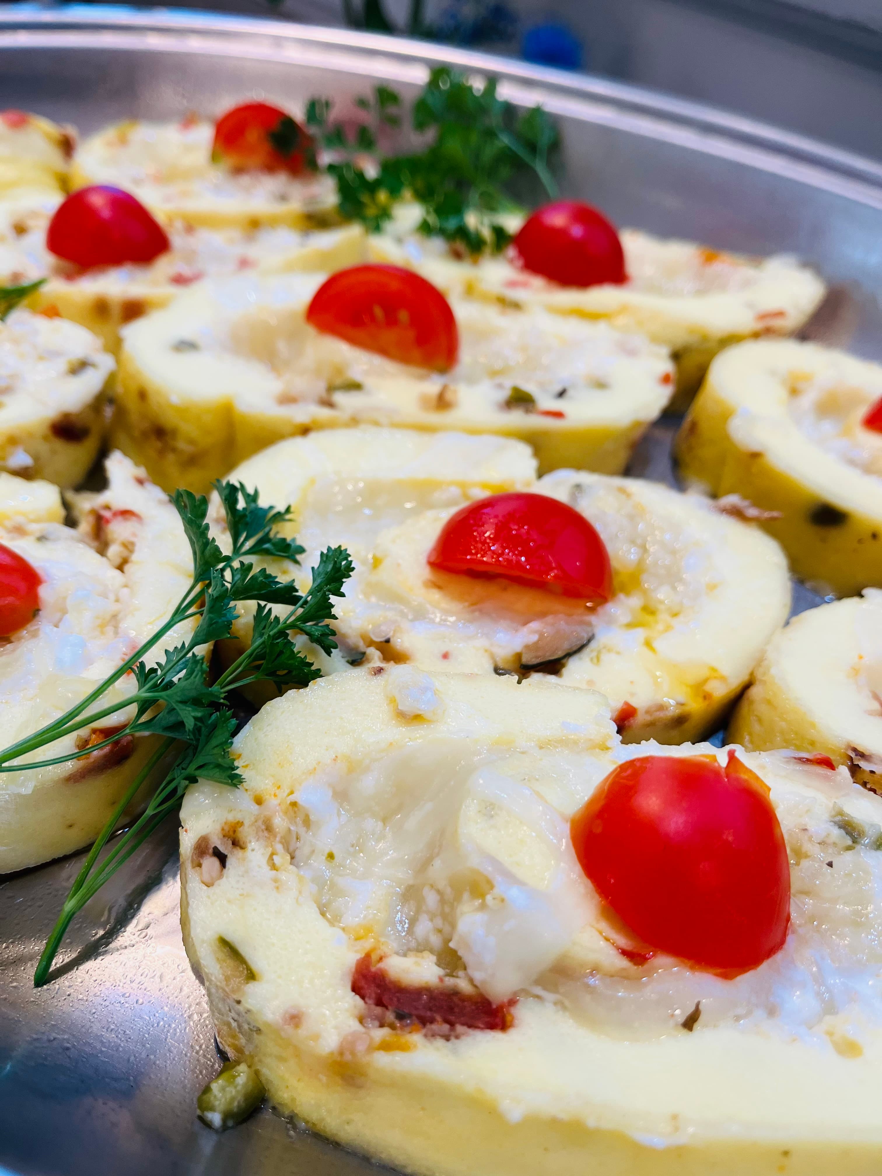 Sliced stuffed potatoes topped with cherry tomatoes and parsley.
