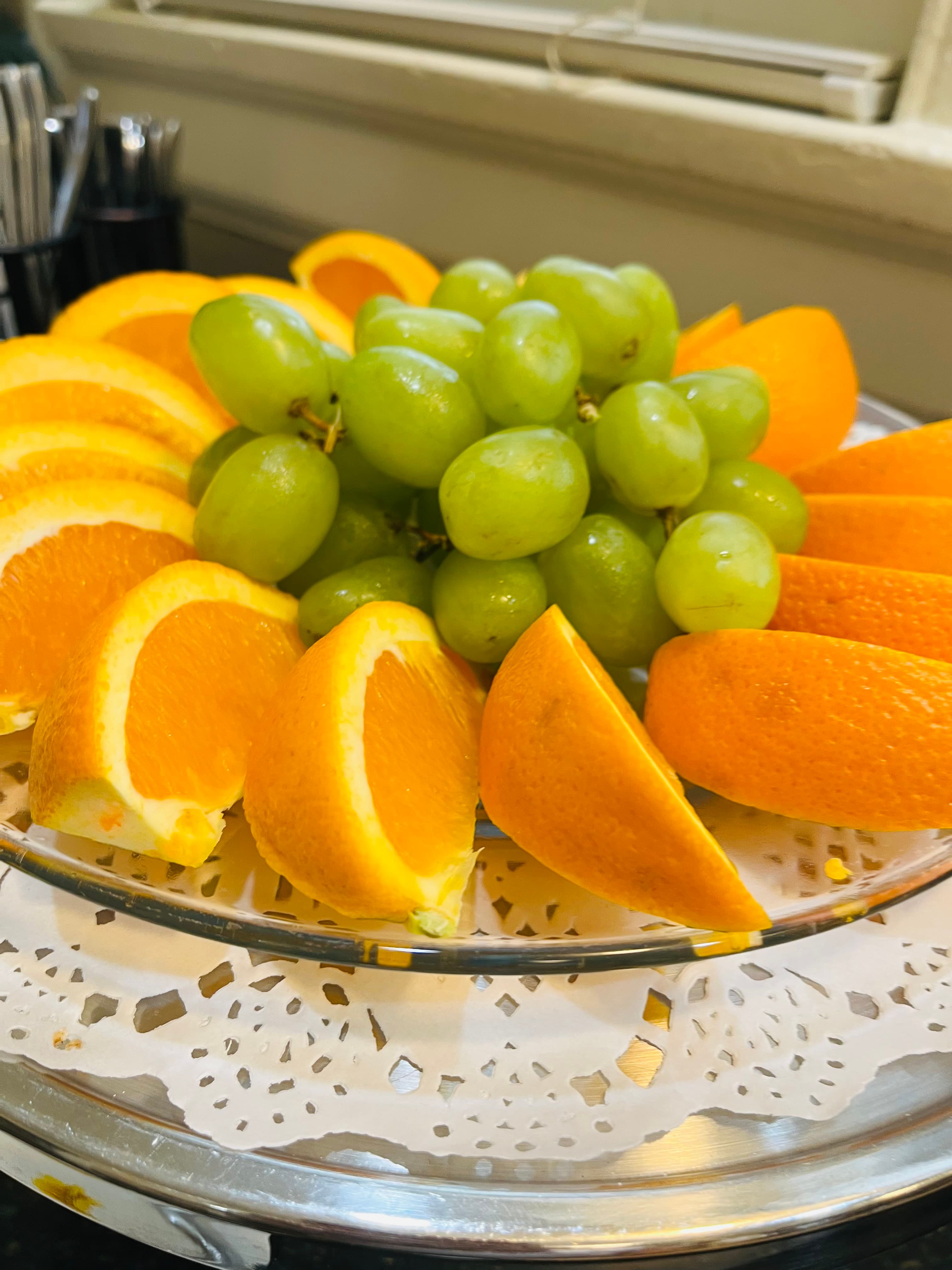 A platter of sliced oranges and green grapes arranged in a decorative manner.